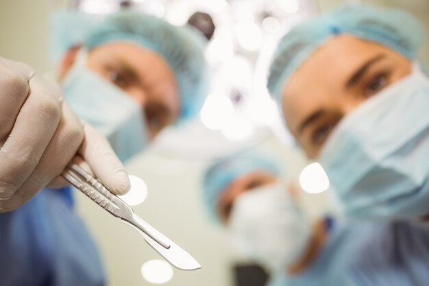 Jeunes chirurgiens regardant la caméra tenant le scalpel