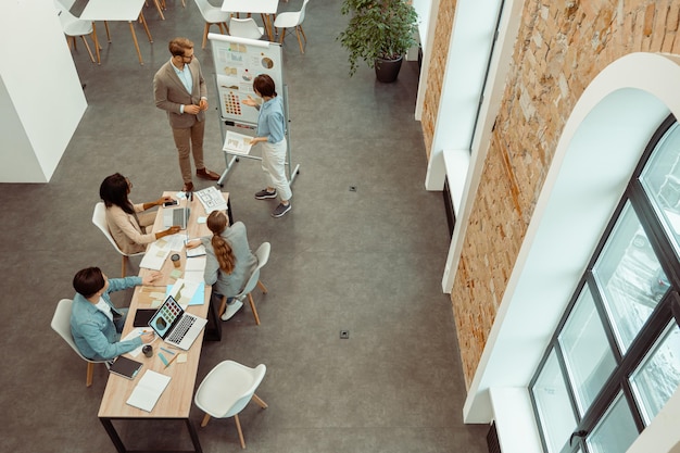 Jeunes collègues debout près du tableau à feuilles mobiles au bureau