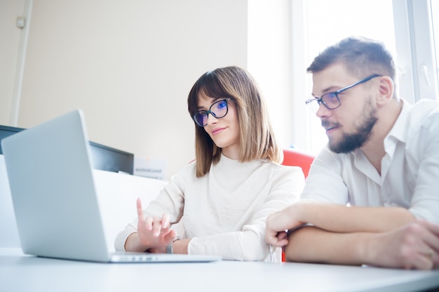 Jeunes collègues utilisant un ordinateur portable au bureau