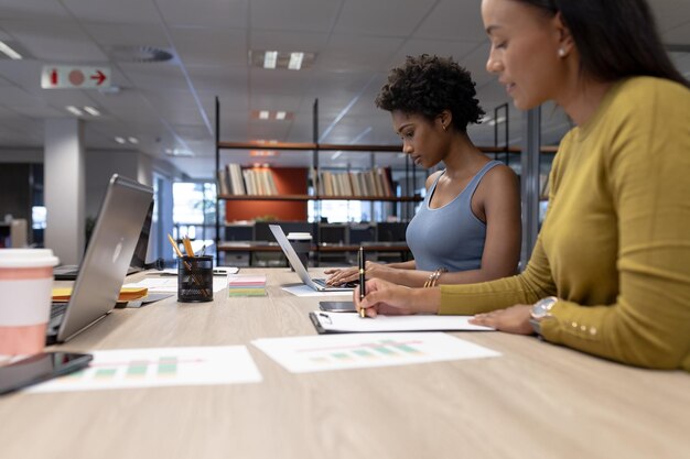 De jeunes conseillères afro-américaines travaillent ensemble à table dans un lieu de travail moderne