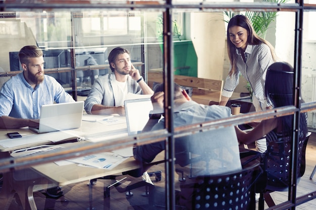 Jeunes créatifs au bureau moderne travaillant avec ordinateur portable, tablette, téléphone intelligent, ordinateur portable