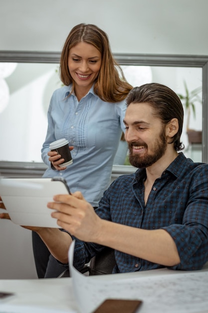 Jeunes designers à succès utilisant une tablette numérique au bureau. Ils analysent le projet et en parlent.