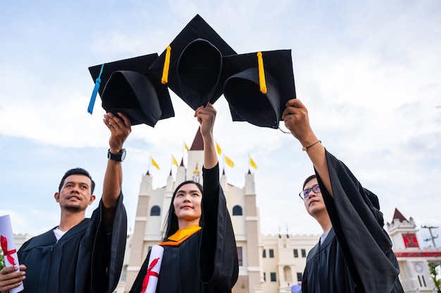 Jeunes Diplômés Asiatiques Tenant Des Chapeaux De Graduation