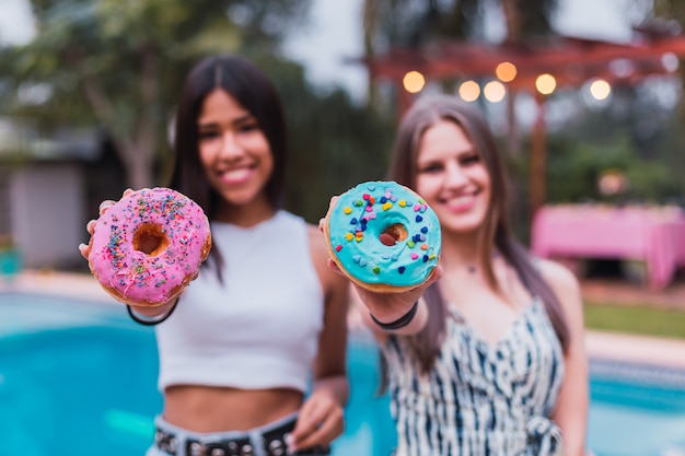 Jeunes drôles avec de délicieux beignets profitant de la journée à la piscine