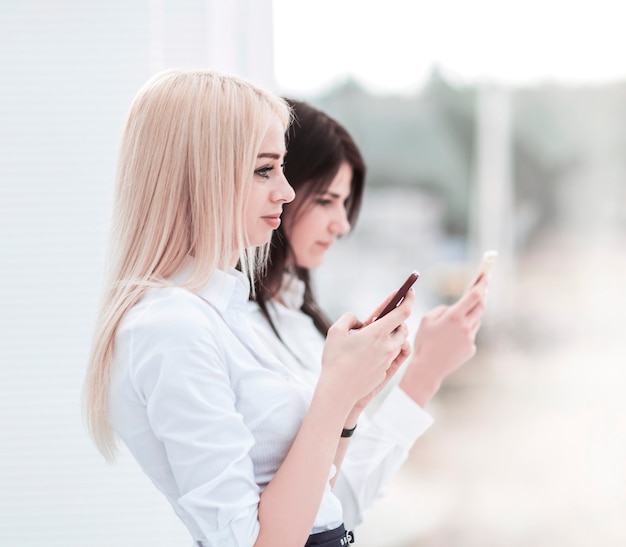 Les jeunes employées de l'entreprise échangent des informations sur un smartphone