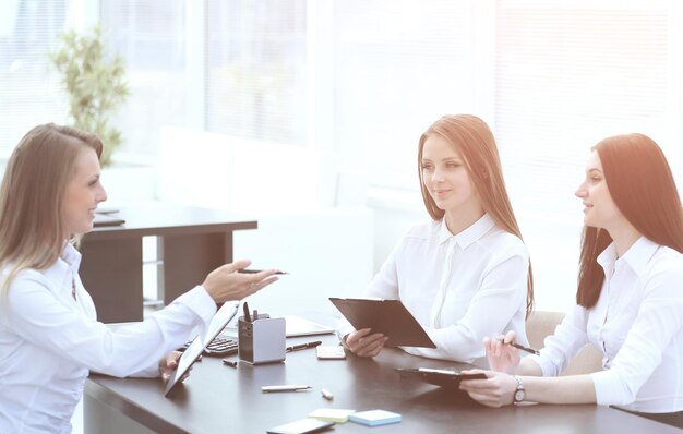 Les jeunes employés parlent assis derrière un bureau