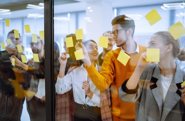 Les jeunes de l'équipe d'affaires réfléchissent ensemble à un projet d'entreprise et écrivent des tâches de stratégie