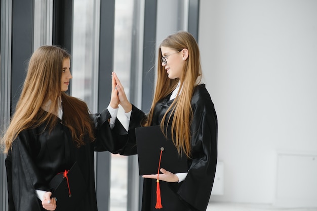 Photo jeunes étudiantes en robe célébrant leur diplôme