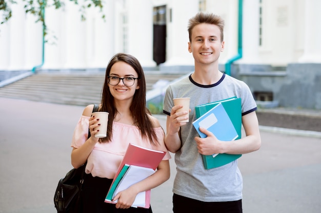 Jeunes étudiants avec du café et du matériel d'apprentissage pendant la pause devant l'université