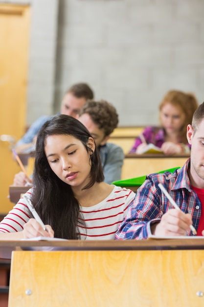 Jeunes étudiants écrivant des notes dans la salle de classe