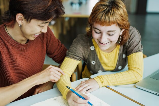 Jeunes étudiants multiraciaux apprenant ensemble à l'intérieur de la bibliothèque de l'université