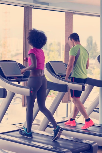 jeunes exerçant un cardio sur un tapis roulant en cours d'exécution dans une salle de sport moderne