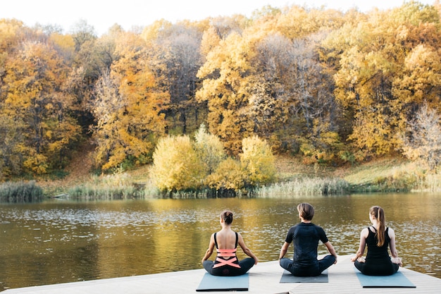 Jeunes faisant du yoga asana dans la nature près du lac