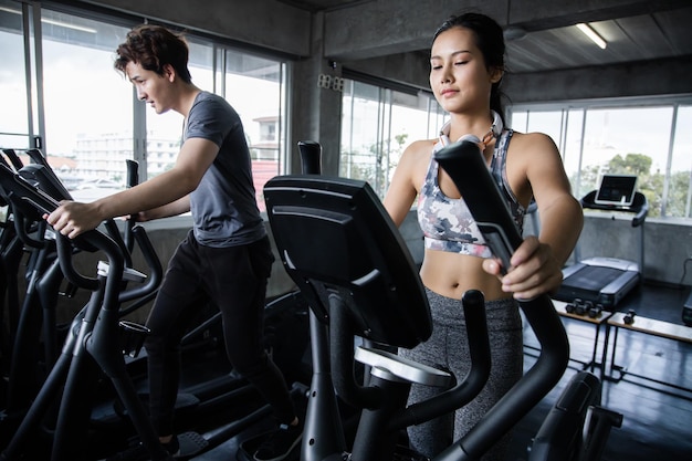 Jeunes faisant des exercices cardio en cours de spinning avec des machines d'exercice dans la salle de gym.