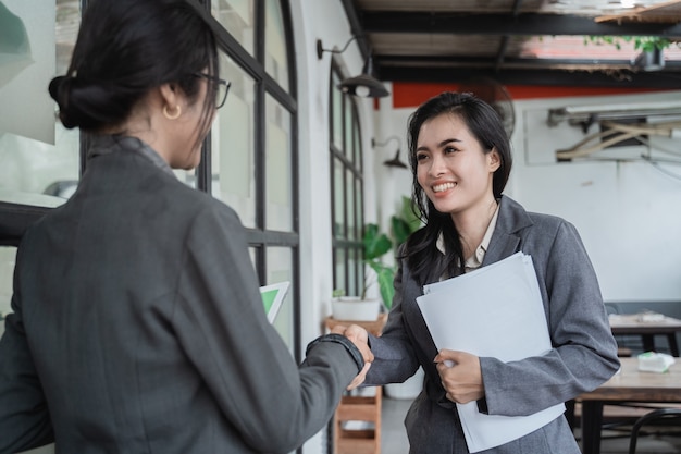 Jeunes femmes d'affaires asiatiques réunies dans un café et serrer la main