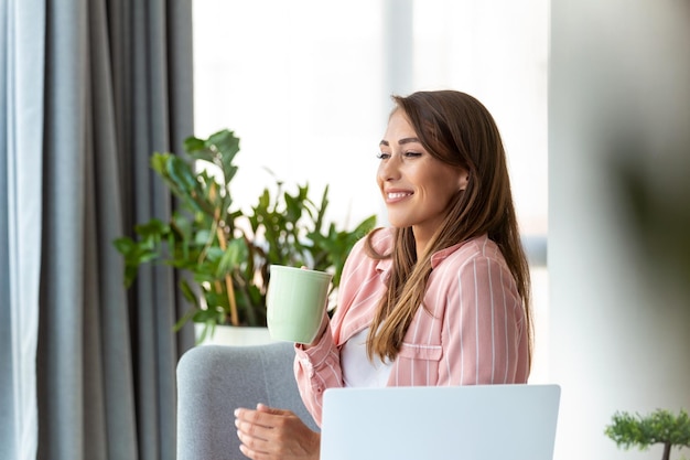 De jeunes femmes d'affaires au bureau buvant du café et regardant par une fenêtre.