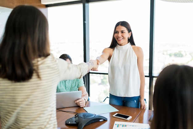 Jeunes femmes d'affaires se serrant la main sur la table dans la salle de réunion au bureau