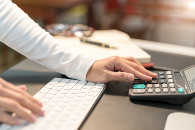 Jeunes femmes d&#39;affaires en tapant sur la calculatrice au bureau