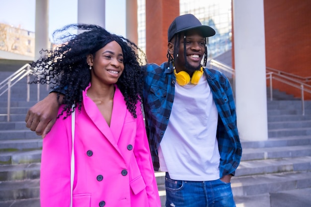 Jeunes femmes afro-américaines dans le style de vie urbain d'amis embrassés marchant en souriant