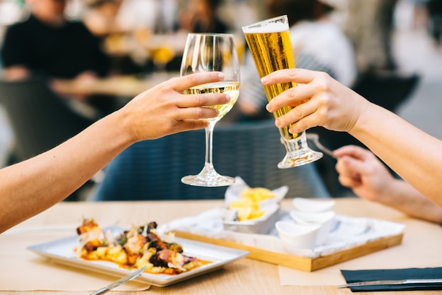 Les jeunes femmes applaudissant la bière et manger de la nourriture sur la terrasse - Deux filles déjeunant ensemble dans un restaurant