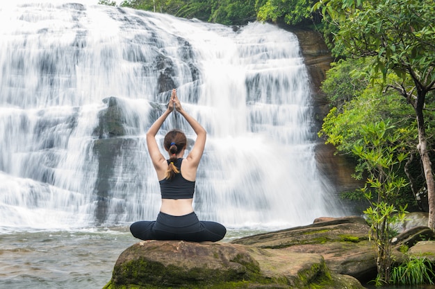 Jeunes femmes asain pratiquant le yoga devant la grande cascade.