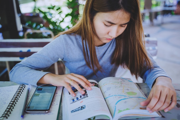 De jeunes femmes asiatiques attrayantes utilisent un smartphone et un carnet de voyage pour planifier leurs vacances