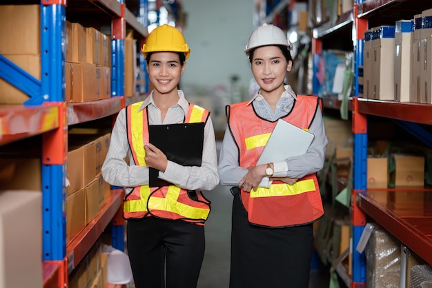 Les jeunes femmes asiatiques en gilets de sécurité debout à l'usine d'entrepôt