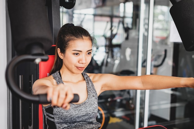 Jeunes femmes asiatiques avec machine d&#39;exercice dans la salle de sport