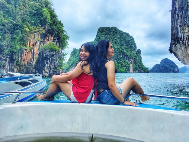 Photo des jeunes femmes assises dos à dos sur un bateau en mer.