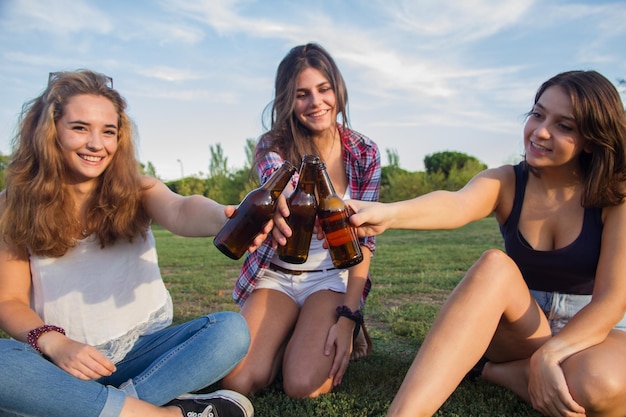 Jeunes femmes buvant de la bière dans le parc