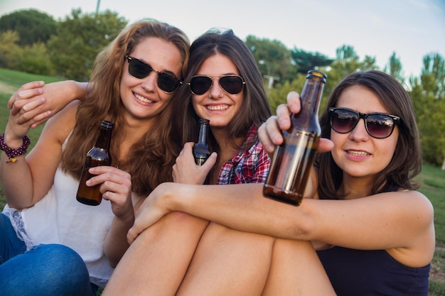 Jeunes femmes buvant de la bière dans le parc