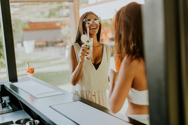 Jeunes femmes buvant un cocktail et s&#39;amusant au bord de la piscine