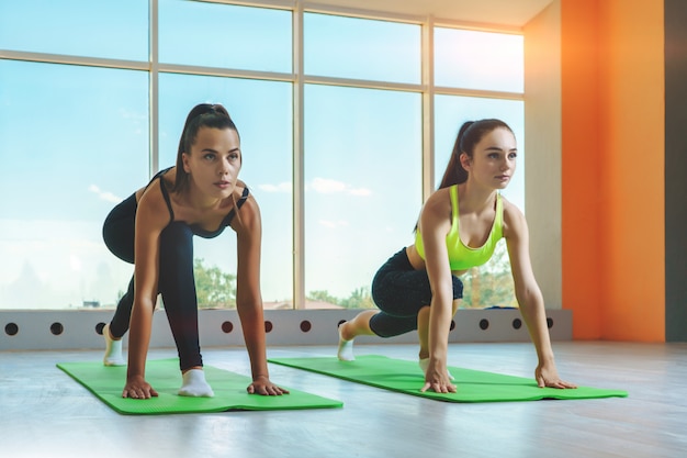 Jeunes femmes caucasiennes qui s'étend dans le studio de remise en forme.