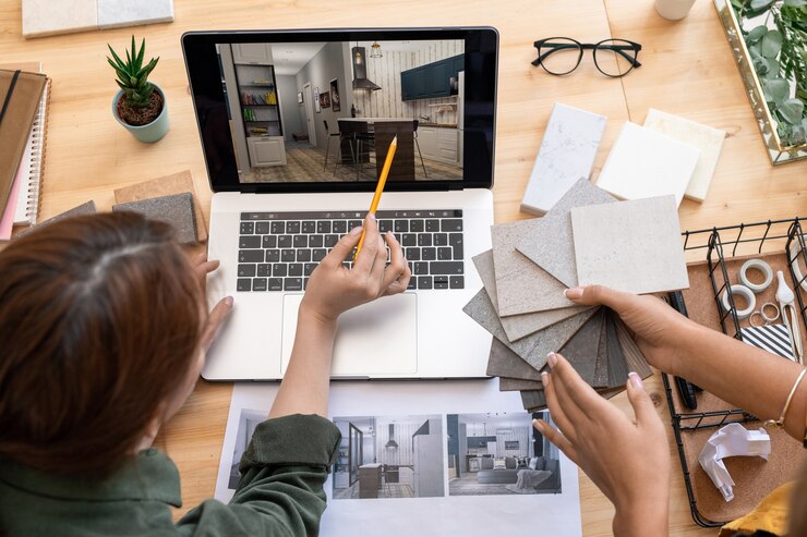 Photo l'une des jeunes femmes avec un crayon pointant sur la table dans l'image de la chambre moderne sur l'écran de l'ordinateur portable tout en discutant de sa conception avec un collègue
