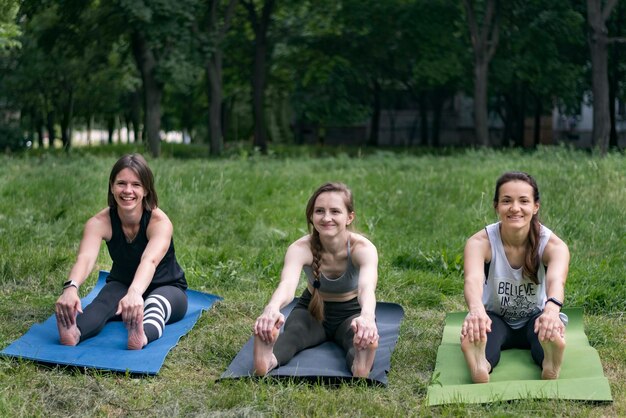 Jeunes femmes effectuant des exercices d'étirement pendant l'entraînement de groupe dans le parc Forme physique et mode de vie sain