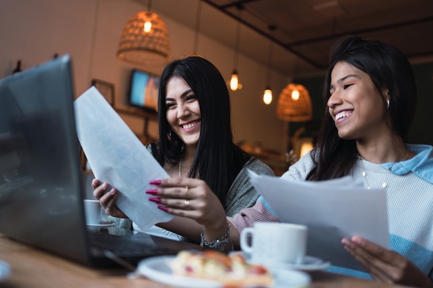 Jeunes femmes étudiant avec leur ordinateur portable dans un bar.