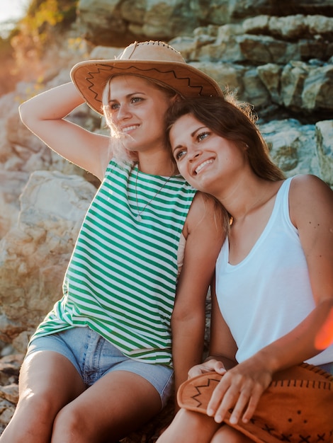 jeunes femmes gaies dans des chapeaux hipsters sur un rocher sur la côte de la mer.