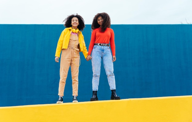 Jeunes femmes heureuses posant sur des murs de couleur bleue et jaune