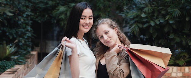 Jeunes femmes métisses asiatiques et métisses portant des sacs à provisions,