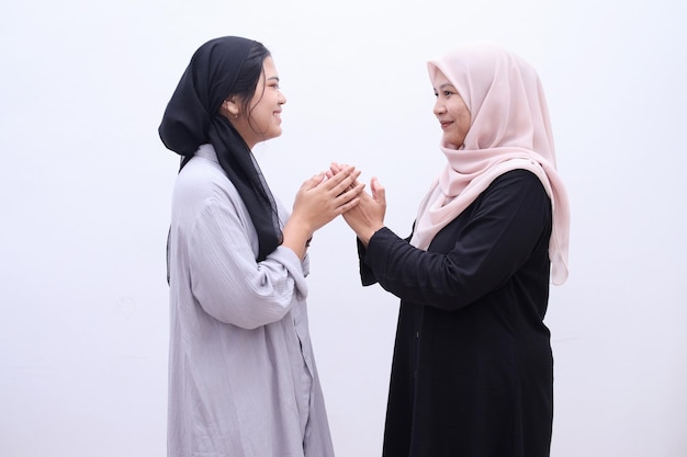 Jeunes femmes musulmanes en hijab se serrant la main, demandant des excuses pendant le moment de l'aïd moubarak.
