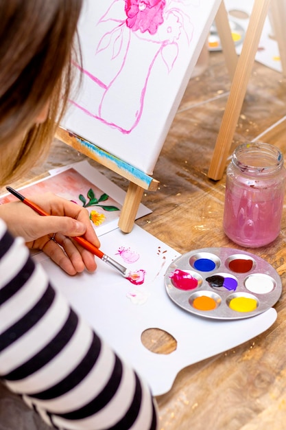 Les jeunes femmes peignent avec un pinceau sur des chevalets dans la classe d'art Concept de créativité et de personnes de l'école d'art