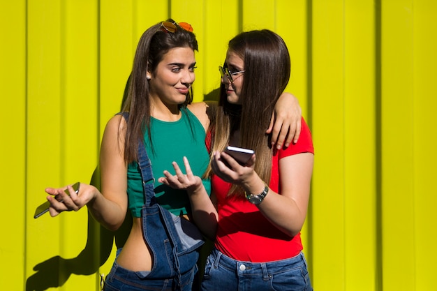 Les jeunes femmes en plein air contre le mur vert écoutent de la musique sur les écouteurs et s'amusent