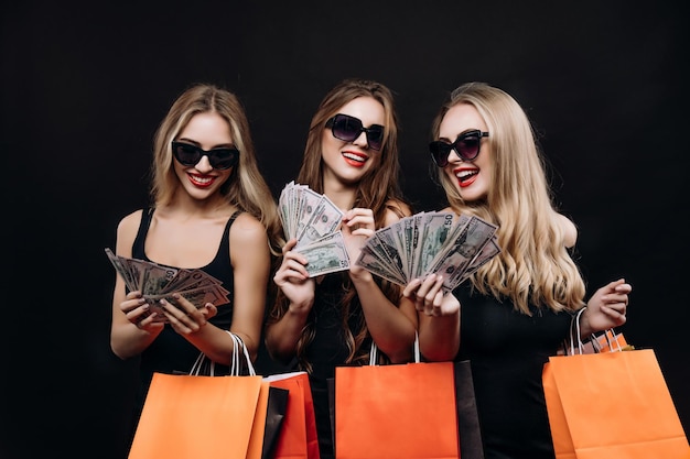 Photo jeunes femmes posant avec des tas de dollars pendant le black friday