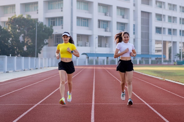 Les jeunes femmes de remise en forme courent sur la piste du stade