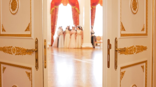Jeunes femmes en robes vintage attrayantes dans la salle de bal portes légèrement ouvertes floues