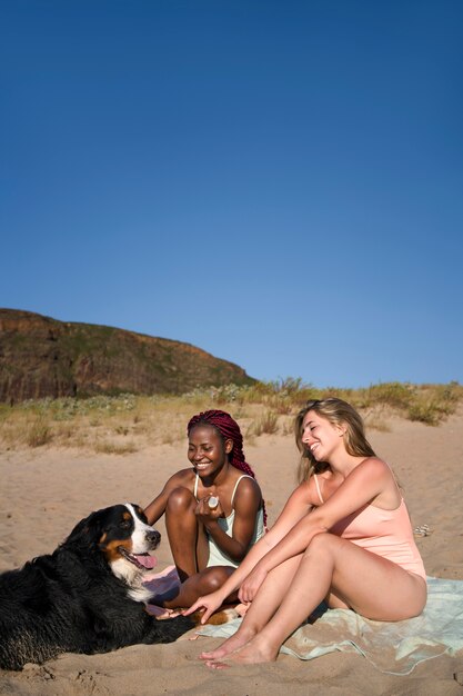 Jeunes femmes s'amusant avec un chien à la plage