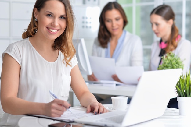 Les jeunes femmes s'assoient à la table et travaillent dans un bureau moderne avec un ordinateur portable