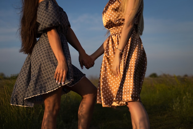 Jeunes femmes se tenant la main sur le terrain. Soleil coucher de soleil d'été.