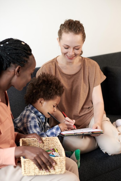 Jeunes femmes souriantes appréciant de dessiner des images avec un fils en bas âge