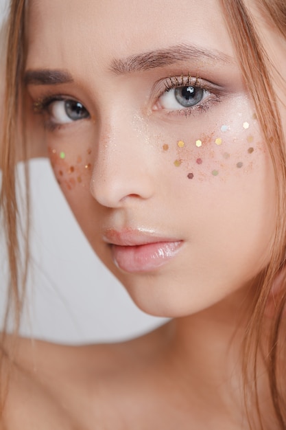 Jeunes femmes avec des taches de rousseur scintillantes sur le visage, belle coiffure